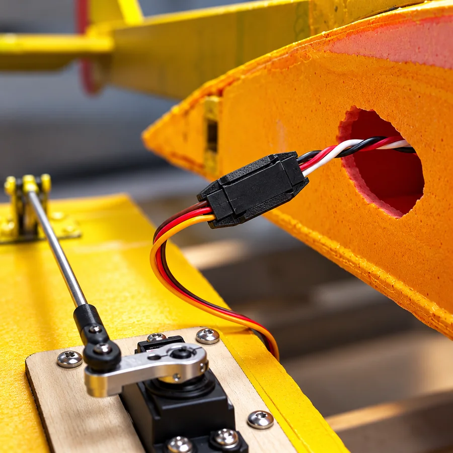 A locked servo extension inside a yellow foam wing, next to the servo and its pushrod